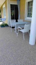 Überdachte Terrasse mit Steinteppich und Sitzbereich – pflegeleicht, langlebig und fugenlos.