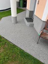 Grauer Steinteppich als fugenlose Oberflaeche im Hauseingang mit passender Stufe und sauberem Wandanschluss
