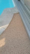 Steinteppich als fugenlose Oberflaeche im Poolbereich mit sauberem Anschluss an Glaswand und Natursteinplatten